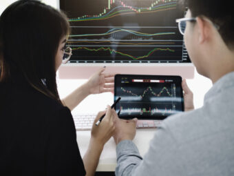 An investment expert points a pen at a tablet monitor to analyze the stock market to teach you how to make a profit.